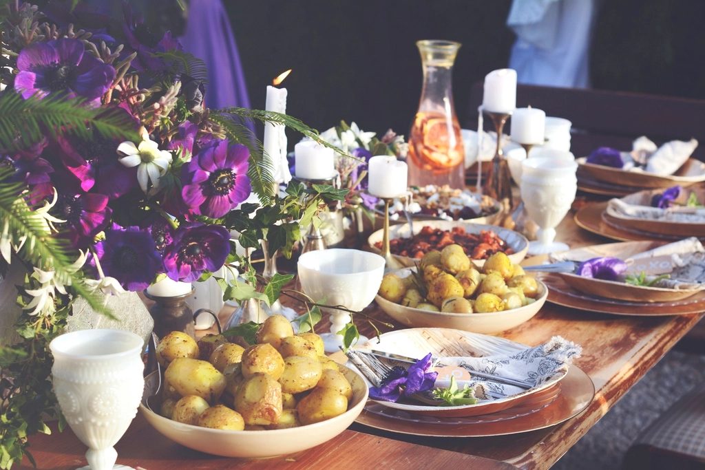 A table spread with dishes, fruit, drinks and flowers