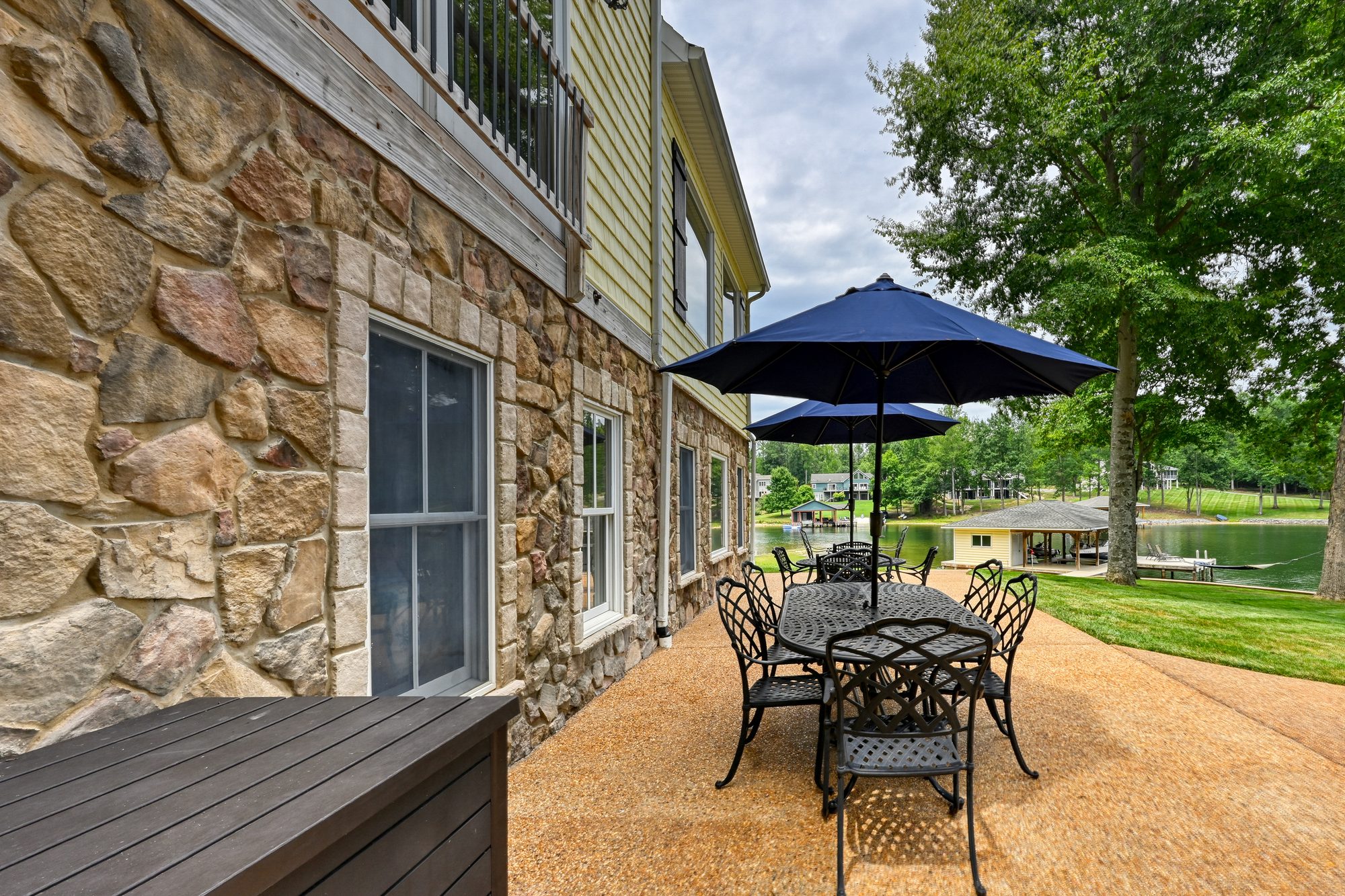Patio dining table under a blue umbrella with the lake beyond