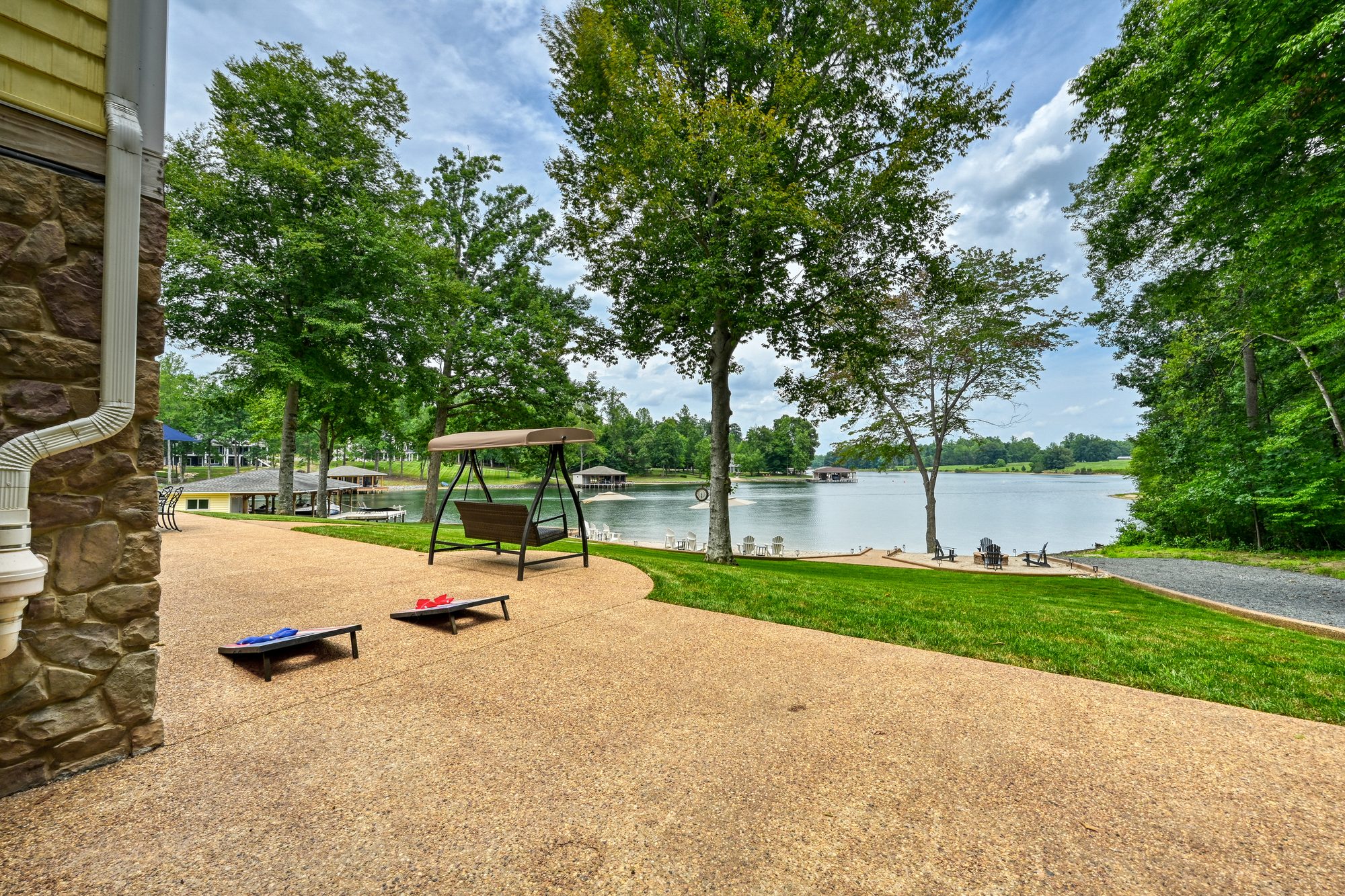 Cornhole boards on the patio with the lawn and lake beyond